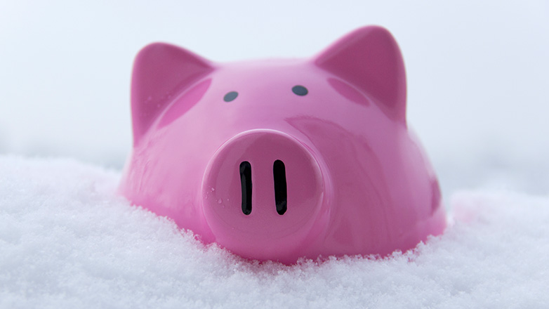 Pink piggy bank sitting in the snow.