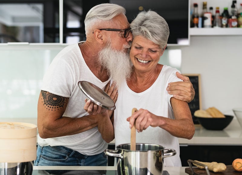 Older couple happily cooking in the kitchen together.